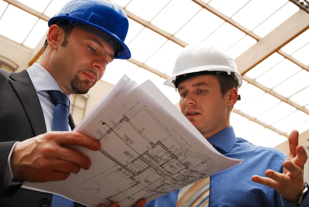 Dos técnicos con casco revisando planos de instalación en obra